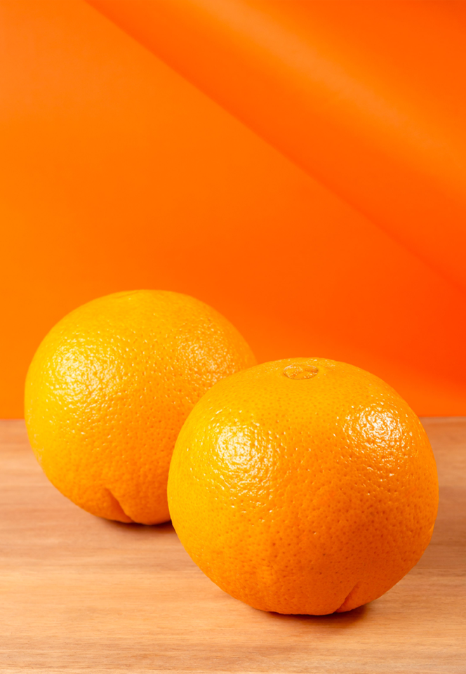 Frame of two oranges on cutting board with orange color background design